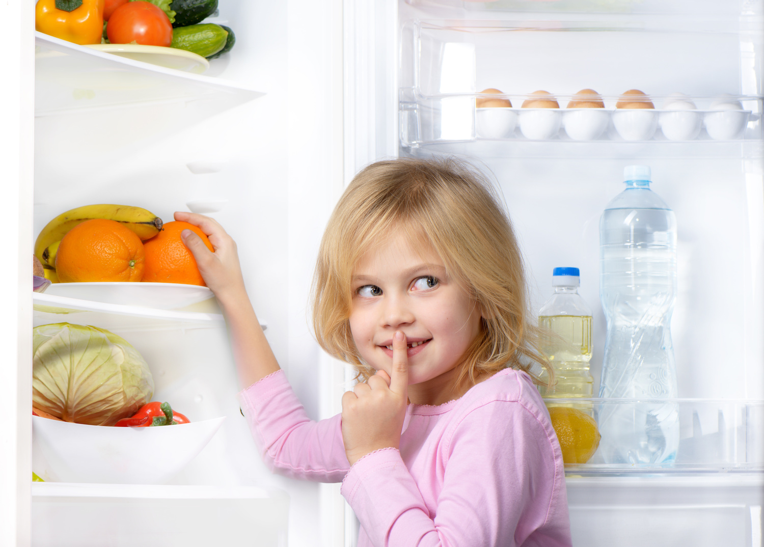 Mädchen vor einem geöffneten Kühlschrank mit Obst und Gemüse